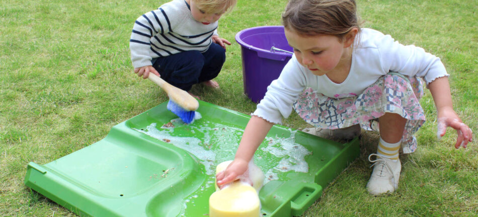 Children giving part of Omlet Eglu Cube chicken coop a clean