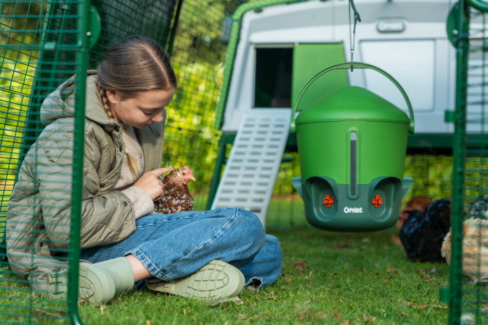 girl holding a chicken in front of an eglu pro chicken coop