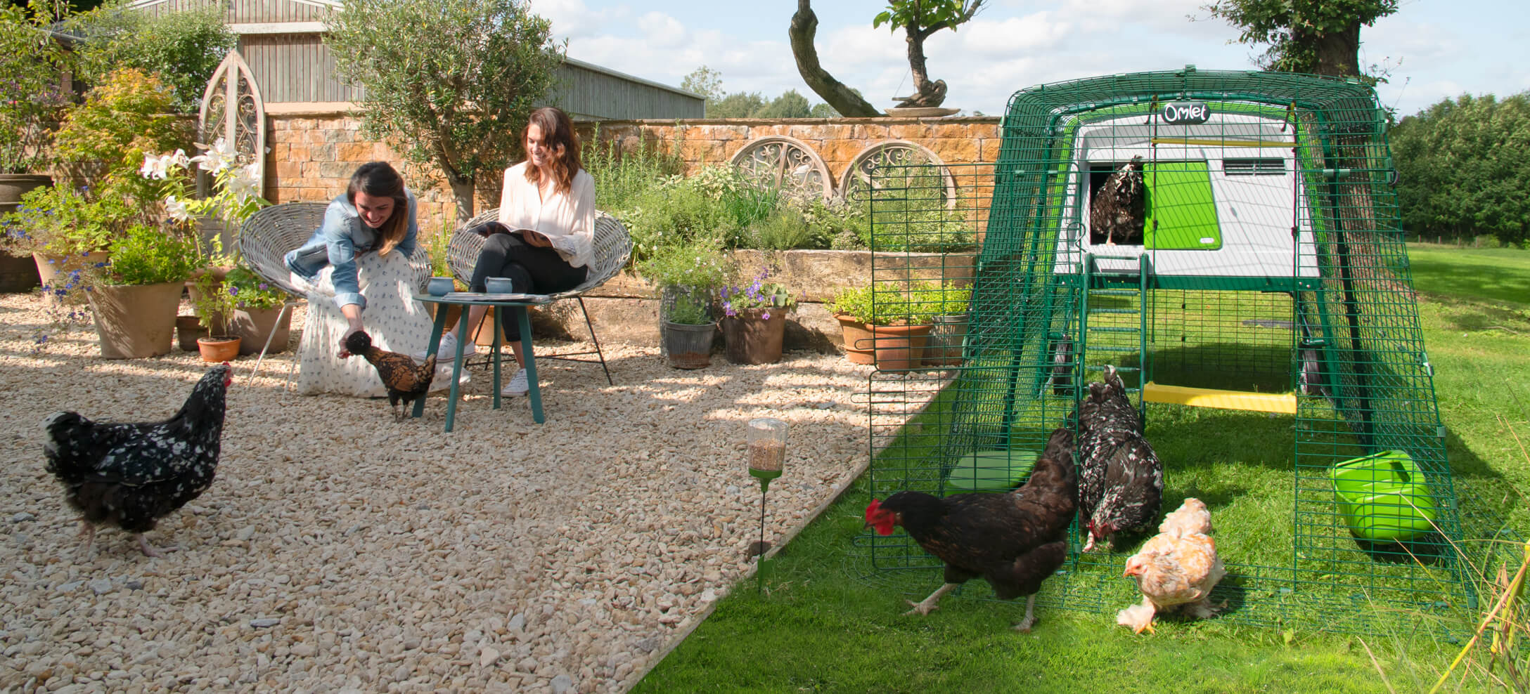 women having tea with their chickens by the large chicken coop eglu cube